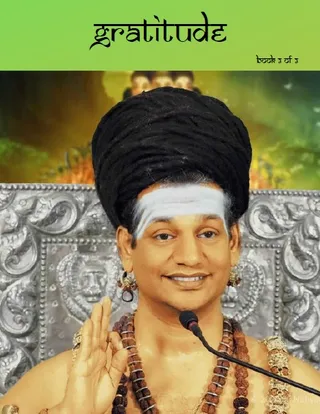 Book cover titled gratitude with a green header band and the subtitle book 3 of 3. Below, a photograph shows a bare-chested man with a tall piled black hair topknot, a white horizontal forehead band, gold earrings, multiple rudraksha mala necklaces and an ornate gold necklace, raising one hand in a blessing gesture before a silver ornate carved backdrop with a microphone in front of him. Behind him, fiery orange and green imagery is visible. The distinctive long piled hair, bare chest and ornate ceremonial adornments match the a person appearance-based label.
