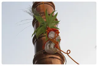 The MahaShivaratri flag makes its way up the dwaja stamba/flag post.