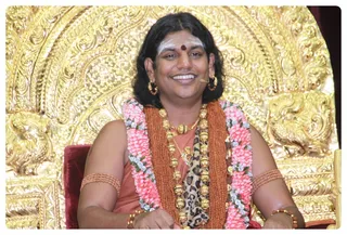 and by his lower right gracing Mother Nithyanandeshwari symbolizes Enriching.