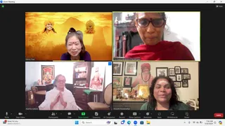 A Zoom video call screenshot showing a four-panel grid of participants. Top left, a woman with short hair and a red bindi smiles in front of a golden-orange backdrop showing a painted figure in orange turban and temple silhouettes. Top right, a woman in red shawl and glasses sits before a shelf with red and white decor. Bottom left, a white-haired woman in a white shawl presses her palms together in namaste in a room with a wooden cabinet and framed deity images. Bottom right, a smiling woman with white forehead marks sits before a wall of framed pictures and a shrine with lit oil lamps, while a standing figure in orange turban and rudraksha mala is visible in a framed picture behind her. Participant names appear on the video tiles, and the Zoom toolbar shows the call controls.