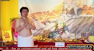 A screenshot from a livestream shows a bare-chested man in a white dhoti standing with palms pressed together in anjali mudra before a ritual altar. He wears a rudraksha mala and a red bindi. Behind him a large mural shows a snow-capped mountain peak with golden cliffs. The altar holds a brass deity murti, a round emblem, a garland of white and red flowers, fruit, oil lamps and a framed photograph. A sign on the table reads KAILASA TAIWAN. A yellow wall and a red cloth hang at the left edge, and a scrolling banner runs along the bottom.