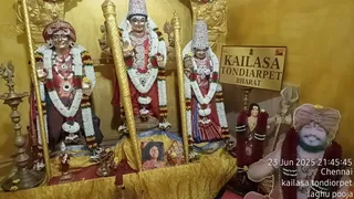 Photograph of a shrine niche with three gold-finished statues draped in white and orange garlands. The left figure wears a red turban and red garments, the centre figure a tall crown and red cloth with a raised hand, and the right figure a silver crown and red sari-like dress holding a small item. A brass oil lamp stands at the left edge and a small framed photograph sits on a gold cloth in front. At the right, a printed sign reads KAILASA TONDIARPET BHARAT beside a large cutout portrait of a smiling man in an orange turban and white clothing with a red garland, next to a trident. Overlaid timestamp reads 23 Jun 2025 21:45:45 Chennai kailasa tondiorpet laghu pooja. No people are physically present.