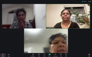 A Zoom video call screenshot with three participant tiles. Top left, a woman in a blue and white checked shirt sits with palms pressed together in namaste before a small shrine. Top right, a woman in a dark top and a pendant necklace sits by a window with potted plants, labelled Shanthi Ravishankar. Bottom centre, a blurred woman with a red bindi and dark hair is labelled Indrani S. The Zoom toolbar shows Audio, Video, Chat, React, Share, AI Companion, Apps and Leave, with 3 participants.