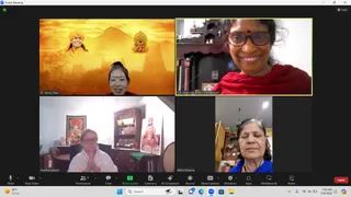 A Zoom meeting screenshot showing four video tiles of women participating from home. Top left, a woman with a red bindi and white garment sits before a golden backdrop showing a turbaned figure, a temple and a mountain. Top right, a smiling woman in glasses and a red shawl with a red bindi sits before a dark wooden shrine with brass lamps and a red-wrapped pillar. Bottom left, a woman in white with palms pressed together in namaste sits before a wall with a deity print of a multi-armed deity and a framed image of a turbaned saint. Bottom right, an older woman with eyes closed wears a blue garment before a shrine with a lit lamp and a small Om symbol. Zoom toolbar icons and a Mute and Leave control appear at the bottom, with the clock reading 7:05 AM.