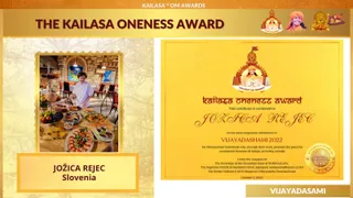 A graphic slide titled "THE KAILASA ONENESS AWARD" under a banner reading "KAILASA OM AWARDS". The left panel shows a photograph of a woman in a white chef's jacket standing behind a buffet table with fruit, bread, platters of food and orange juice in glasses, beside a stone wall and a painted artwork, with a caption reading "JOŽICA REJEC Slovenia". The right panel shows a gold certificate for the Kailasa Oneness Award conferred to "JOZICA REJEC" for Vijayadashami 2022, dated October 5, 2022, under the auspices of the Sovereign of the Sovereign State of SHRIKAILASA, with a round gold seal and small emblems of a deity and a saffron-robed figure at the top. A "VIJAYADASAMI" label appears at the bottom right. The slide has no physical people beyond the printed photograph.